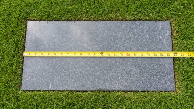 Flat granite grave markers in three sizes laid side by side on grass with a measuring tape
